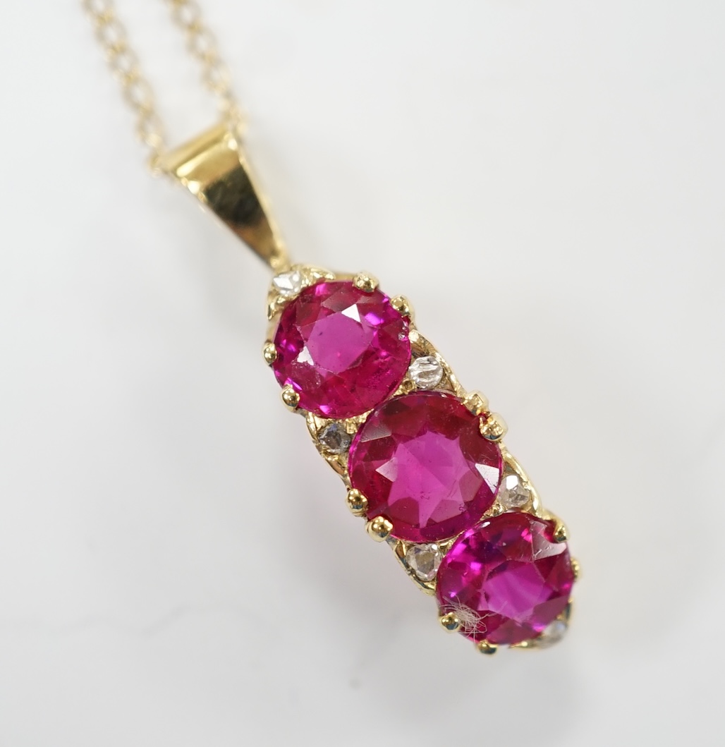 A modern 18ct gold and three stone synthetic ruby set curved pendant, with diamond chip set spacers, overall 27mm, on a 375 chain, 48cm, gross weight 4.8 grams. Condition - fair